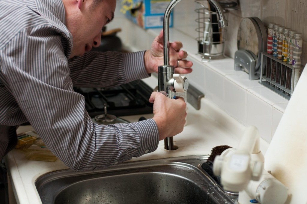 man replacing kitchen faucet